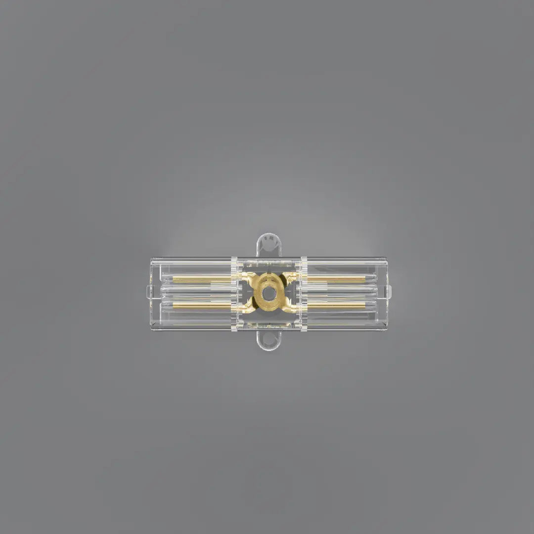A clear plastic rectangular component with gold-colored internal rods and a circular gold center, shown against a solid gray background.